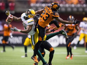 D'haquille Williams of the Edmonton Eskimos, left, can't come up with the ball after colliding with B.C. Lions' defender Anthony Thompson and Garry Peters, back, during Thursday's CFL game at B.C. Place Stadium. The Lions erased a 20-10 deficit and won 31-23.