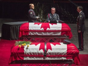Members of the Fredericton Police Force place medals, hat and ceremonial belt on the casket for Const. Robb Costello at the regimental funeral for Costello and Const. Sara Burns, killed in the line of duty, in Fredericton on Saturday, Aug. 18, 2018.
