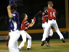 Canada's Joey Marino, center, is mobbed by teammates Cole Balkovec, left and Kai Scheck after delivering the winning hit in the 10th inning as Spain's pitcher Toni Cortes walks off the field of an elimination baseball game in International pool play at the Little League World Series tournament in South Williamsport, Pa., Saturday, Aug. 18, 2018.