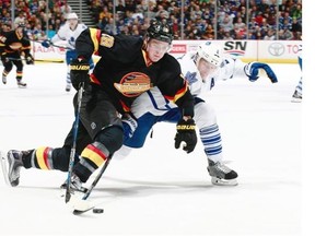 Vancouver Canucks forward Jake Virtanen puts the moves on Toronto Maple Leafs’ defenceman Matt Hunwick while wearing a throwback uniform.