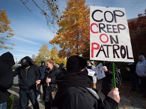 A woman hiding her face holds a sign as members of the vigilante group Surrey Creep Catchers and their supporters gather outside B.C. provincial court in Surrey for the appearance of an RCMP constable accused of child-luring in October 2016.