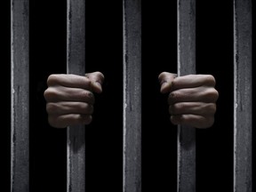 Photo illustration of hands grasping prison bars.