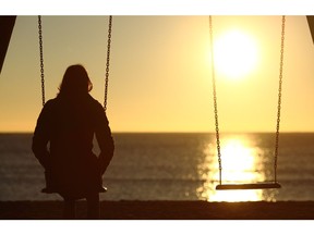 Lonely woman watching sunset alone in winter on the beach at sunset.