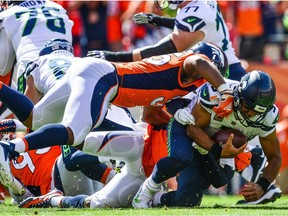 Quarterback Russell Wilson of the Seattle Seahawks is sacked by defensive back Darian Stewart and linebacker Bradley Chubb of the Denver Broncos.