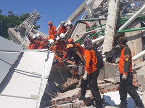 This handout was taken Sept. 30 and released by Indonesia's National Search and Rescue Agency showing rescuers retrieving a body from the rubble of a building in Palu, Indonesia's Central Sulawesi, after the Sept. 28 earthquake and tsunami.