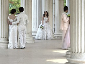 A bride waits for her groom as other couples pose for wedding photos at a park in Beijing, China, April 13, 2014.