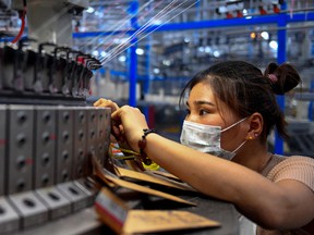 An employee checks on a circular weaving machine at a textile factory in Shangqiu in China's central Henan province. China is in for job losses amid an escalating trade war with the U.S.