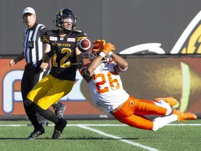 The ball slips through the hands of B.C. Lions defensive back Anthony Orange, right, straight into the hands of Hamilton Tiger-Cats wide receiver Mike Jones during Saturday's CFL game action in Hamilton. The Lions lost 40-10.