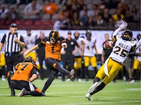 B.C. Lions' Ty Long (1) kicks the game-winning field goal as quarterback Cody Fajardo (17) holds while Hamilton Tiger-Cats' Jumal Rolle (25) defends during the second overtime of a CFL football game in Vancouver, on Saturday September 22, 2018.