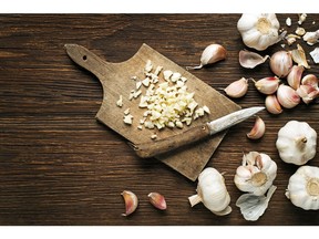 Garlic cloves and sliced garlic on vintage wooden background. Getty Images/iStockphoto