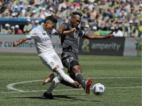 Seattle Sounders forward Raul Ruidiaz, left, kicks the ball past Vancouver Whitecaps defender Kendall Waston, right, during the second half of an MLS soccer match Saturday, July 21, 2018, in Seattle. The Sounders won 2-0.