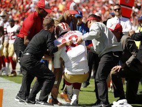 Trainers lift injured San Francisco 49ers quarterback Jimmy Garoppolo (10) who was hurt after a tackle by Kansas City Chiefs defensive back Steven Nelson during the second half of an NFL football game in Kansas City, Mo., Sunday, Sept. 23, 2018.