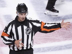 In this photo taken Sept. 17, 2018, referee Wes McCauley, top, calls a penalty as the Montreal Canadiens face the New Jersey Devils during preseason NHL hockey game action in Montreal. An informal poll of NHL players leaves no doubt as to who the most popular referee is: Veteran McCauley.