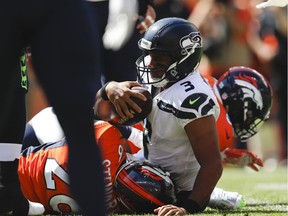 Seattle Seahawks quarterback Russell Wilson, center, is sacked by Denver Broncos linebacker Bradley Chubb, right, and defensive back Darian Stewart, left, during the first half of an NFL football game Sunday, Sept. 9, 2018, in Denver.