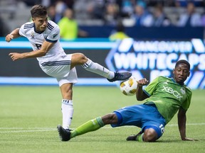 Vancouver Whitecaps' Nicolas Mezquida, left, has his shot blocked by Seattle Sounders' Kelvin Leerdam during the first half of an MLS soccer game in Vancouver, on Saturday September 15, 2018.