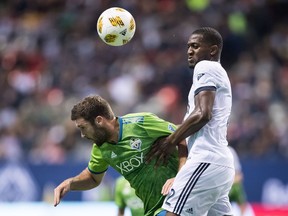 Seattle Sounders' Will Bruin, left, and Vancouver Whitecaps' Doneil Henry vie for the ball during the second half of an MLS soccer game in Vancouver, on Saturday September 15, 2018.