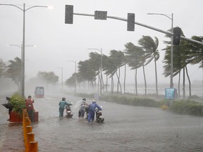 Motorists brave the rain and strong winds brought about by Typhoon Mangkhut which barreled into northeastern Philippines before dawn Saturday, Sept. 15, 2018 in Manila, Philippines.