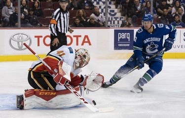 Goalie Mike Smith #41 of the Calgary Flames makes a save while Jay Beagle #83 of the Vancouver Canucks looks for a rebound in NHL action on October, 3, 2018 at Rogers Arena in Vancouver, British Columbia, Canada.