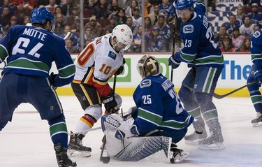 Derek Ryan #10 of the Calgary Flames is stopped by Jacob Markstrom #25 of the Vancouver Canucks in close in NHL action on October, 3, 2018 at Rogers Arena in Vancouver, British Columbia, Canada. Tyler Motte #64 and Alexander Edler #23 of the  Canucks look on during the play.