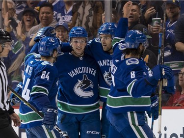 Jake Virtanen #18 of the Vancouver Canucks is congratulated by teammates Tyler Motte #64, Brandon Sutter #20 and Chris Tanev #8 after scoring a goal against the Calgary Flames in NHL action on October, 3, 2018 at Rogers Arena in Vancouver, British Columbia, Canada.