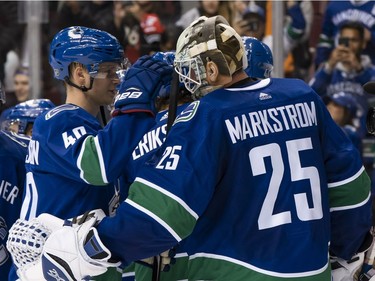 Goalie Jacob Markstrom  is congratulated by teammate Elias Pettersson after a win over the Calgary Flames.
