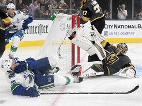 Antoine Roussel of the Vancouver Canucks and Marc-Andre Fleury of the Vegas Golden Knights fall to the ice in the first period.