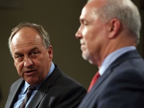 Green party Leader Andrew Weaver speaks to the media as Premier John Horgan and looks on.