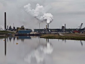 The Syncrude oil sands extraction facility is reflected in a tailings pond near the city of Fort McMurray, Alberta on June 1, 2014.The National Energy Board on Friday laid out its schedule for the Trans Mountain pipeline hearings process, as well as a new report that will weigh the environmental impact of increased tanker traffic on the BC coast. It comes as the gap between Canadian and US oil prices reaches its highest in more than five years.
