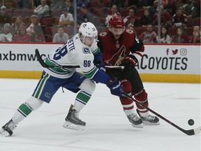 Arizona Coyotes defenseman Jason Demers gets called for hooking on Vancouver Canucks center Adam Gaudette (88) in the third period during an NHL hockey game, Thursday, Oct. 25, 2018, in Glendale, Ariz. Arizona defeated Vancouver 4-1.