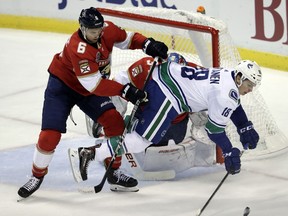 Vancouver Canucks right wing Jake Virtanen (18) falls to the ice as he goes for the puck against Florida Panthers defenseman Alexander Petrovic (6) during the first period of an NHL hockey game, Saturday, Oct. 13, 2018, in Sunrise, Fla.