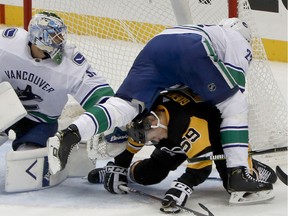 Vancouver Canucks' Alexander Edler, top right, tumbles over Pittsburgh Penguins' Jake Guentzel (59) beside goaltender Anders Nilsson during the first period of an NHL hockey game, Tuesday, Oct. 16, 2018, in Pittsburgh.