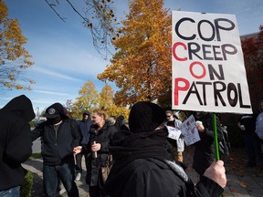 A woman hiding her face holds a sign as members of the vigilante group Surrey Creep Catchers and their supporters gather outside B.C. Provincial Court at a scheduled court appearance for RCMP Const. Dario Devic, who was charged with luring a child after the group alleged a man was trying to solicit an underage girl for sex, in Surrey, B.C., on Wednesday October 19, 2016. THE CANADIAN PRESS/Darryl Dyck ORG XMIT: VCRD105