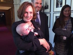 British Columbia Energy Minister Michelle Mungall holds her son Zavier, almost 3 months old, as she walks with her husband Zak along a corridor at the legislature in Victoria on Monday, Oct. 15, 2018. Baby Zavier is first child permitted on floor of the British Columbia legislature chamber since legislation last spring where all parties voted to allow children on floor of legislature.
