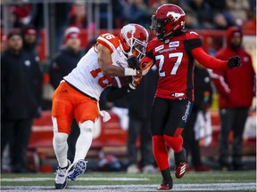 BC Lions' Bryan Burnham, left, manages catch and hang onto the ball as Calgary Stampeders' Tunde Adeleke tries to knock it free during CFL football action in Calgary, Saturday, Oct. 13, 2018.