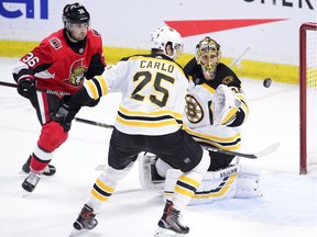 Boston Bruins goaltender Tuukka Rask and teammate Brandon Carlo keep their on the puck as Ottawa Senators center Colin White looks on during second period NHL hockey action in Ottawa on Tuesday, Oct. 23, 2018.