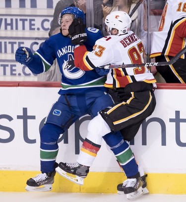 Calgary Flames center Sam Bennett (93) puts Vancouver Canucks right wing Brock Boeser (6) into the boards during second period NHL action at Rogers Arena in Vancouver, Wednesday, Oct, 3, 2018.