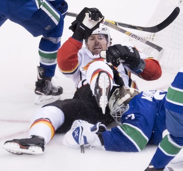 Calgary Flames left wing James Neal (18) falls over Vancouver Canucks goaltender Jacob Markstrom (25) during second period NHL action at Rogers Arena in Vancouver, Wednesday, Oct, 3, 2018.