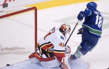 Vancouver Canucks right wing Jake Virtanen (18) sends a shot past Calgary Flames goaltender Mike Smith (41) during third period NHL action at Rogers Arena in Vancouver, Wednesday, Oct, 3, 2018.