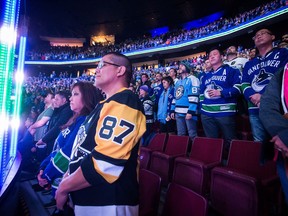 Spectators stand during a moment of silence for the victims of a shooting at a Pittsburgh synagogue, before the Vancouver Canucks and Pittsburgh Penguins play an NHL hockey game, in Vancouver, on Saturday October 27, 2018.
