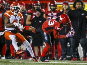 BC Lions' T.J. Lee, left, hauls down Calgary Stampeders' Markeith Ambles by his foot during CFL football action in Calgary, Saturday, Oct. 13, 2018.