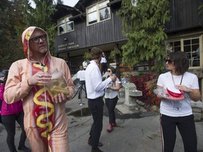 "Extraction experts" gives free samples of Hotdog Water to people outside the Goop Summit in Stanley Park in Vancouver on Saturday. The Hotdog Water is a parody of healthy lifestyle marketing products, and is a concept devised by artist Douglas Bevans, left, as an exercise in critical thinking.