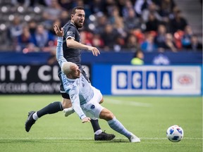 Sporting Kansas City's Yohan Croizet, front, falls as he and Vancouver Whitecaps' Jordon Mutch chase after the ball.