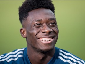 Vancouver Whitecaps midfielder Alphonso Davies laughs while talking to a teammate as he waits to begin an interview after MLS soccer practice in Vancouver, on Wednesday. Davies is scheduled to play his last game as a member of the Whitecaps Sunday after signing with Bayern Munich earlier this year.