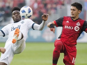 Vancouver Whitecaps forward Alphonso Davies, left, battles for the ball Saturday against Toronto FC midfielder Marco Delgado during first half MLS action in Toronto. The Whitecaps won 2-1.