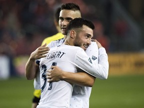 Vancouver Whitecaps midfielder Russell Teibert hugs teammate Jake Nerwinski after defeating the Toronto FC during second half MLS soccer action in Toronto on Saturday, Oct. 6, 2018.