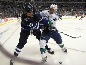 Winnipeg Jets, defenceman Dustin Byfuglien, left, battles for a loose puck with Vancouver Canucks' forward Antoine Roussel in Winnipeg on Thursday night. The Jets won 4-1.