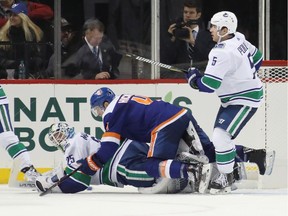 Thomas Hickey of the New York Islanders lands on top of Jacob Markstrom late in the third period of the Islanders' 5-2 win.