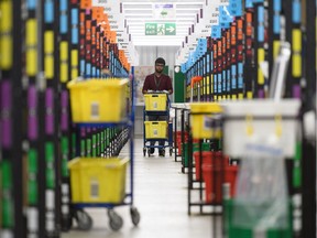 A member of staff picks customer orders from the storage shelves at the Amazon Fulfillment Centre on Nov. 14, 2018, as Black Friday shopping is about to begin.