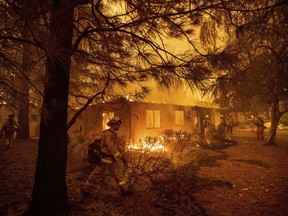 Firefighters work to keep flames from spreading through the Shadowbrook apartment complex as a wildfire burns through Paradise, Calif., on Friday, Nov. 9, 2018.