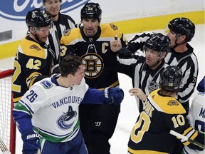 Referees separate Vancouver Canucks left wing Antoine Roussel (26) and Boston Bruins right wing David Backes (42), defenseman Zdeno Chara (33) and left wing Anders Bjork (10) during the first period of an NHL hockey game Thursday, Nov. 8, 2018, in Boston.